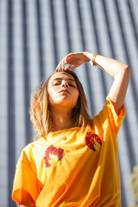 Low angle portrait of young woman standing against building