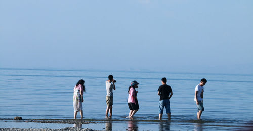 People on shore against clear blue sky