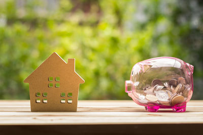 Close-up of house model and piggy bank on table