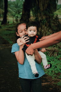 Cropped hands of mother taking daughter held by sister at park