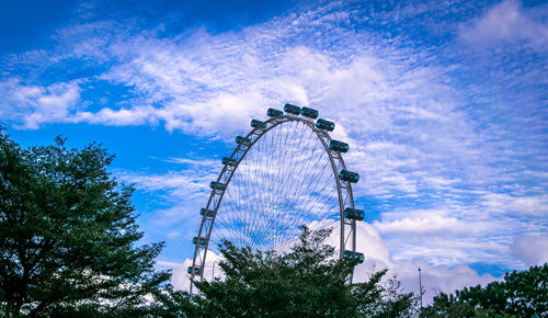 Low angle view of ferris wheel against cloudy sky