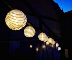 Low angle view of illuminated light bulb hanging from ceiling