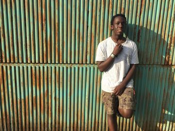 Portrait of teenage boy standing against metal