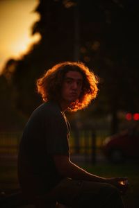 Portrait of mid adult man with wavy hair while sitting outdoors