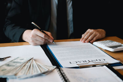 Midsection of man reading book on table