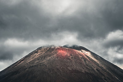 Scenic view of volcanic mountain against cloudy sky