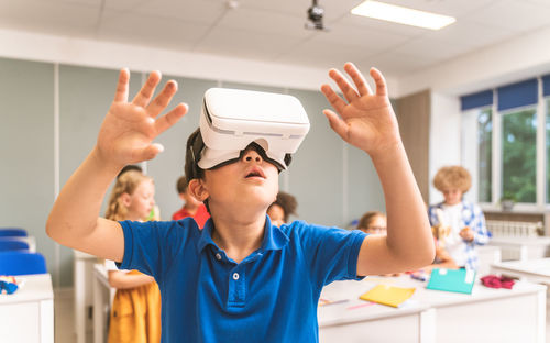 Cute boy using virtual reality simulator in classroom