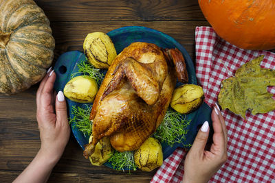 Women's hands serve freshly cooked chicken with potatoes and micro greenery on the table