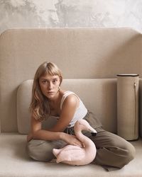 Portrait of woman sitting against wall at home