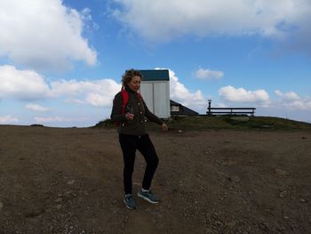 Full length of mature woman walking on field against cloudy sky