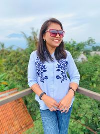 Portrait of smiling young woman wearing sunglasses standing outdoors