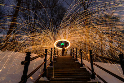 Person standing at illuminated footbridge during night