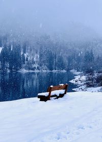 Scenic view of snowcapped field by lake during winter