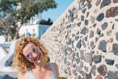 Young woman wearing sunglasses while standing against wall