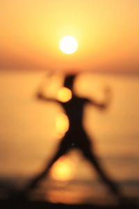 Close-up of silhouette person against sea during sunset