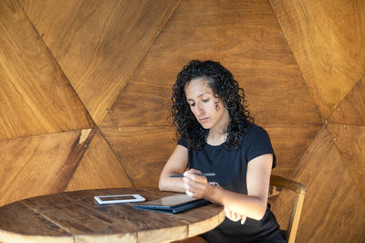 Woman using a digital tablet while sitting at a table.