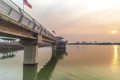 Bridge over river against sky during sunset