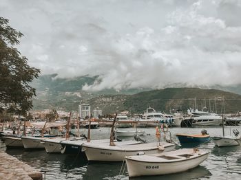 Boats moored at harbor against sky