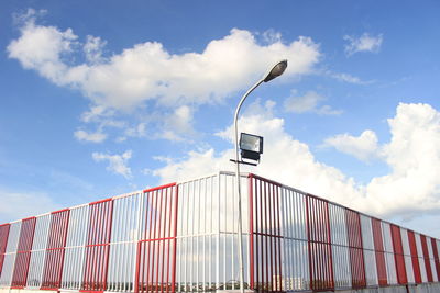 Low angle view of street light by building against sky