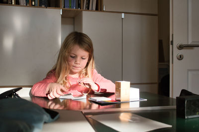 Portrait of girl sitting on table at home