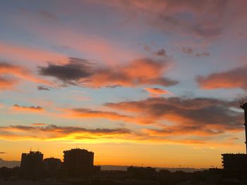 Silhouette buildings against dramatic sky during sunset