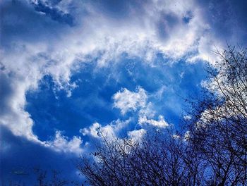 Low angle view of bare tree against cloudy sky