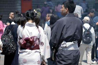 Rear view of people walking on street in city