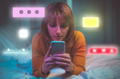 Mid adult woman using mobile phone while sitting on bed