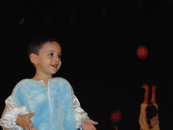 Smiling boy looking away while standing outdoors at night