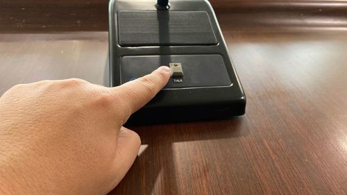 Close-up of hand touching microphone on table