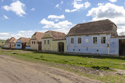 Houses on field by buildings against sky