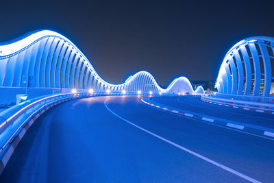 View of illuminated bridge against blue sky at night