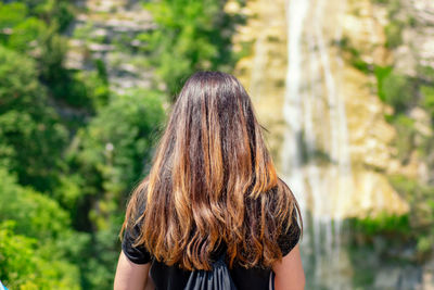 Rear view of woman standing against trees