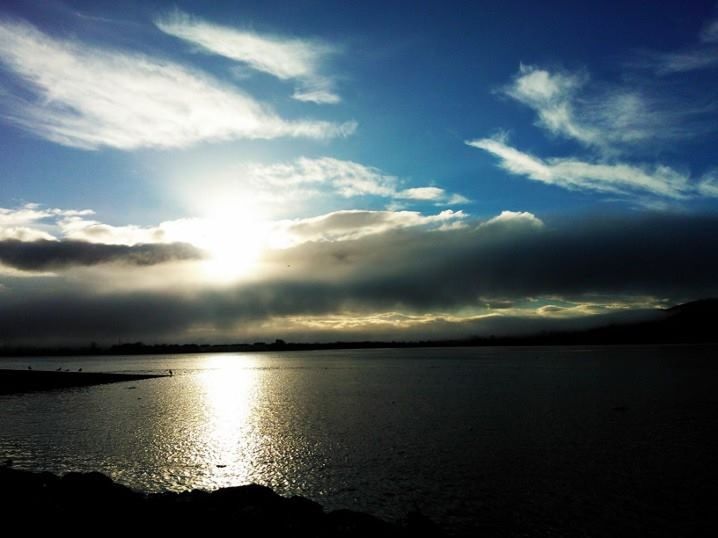 SUN SHINING THROUGH CLOUDS OVER SEA