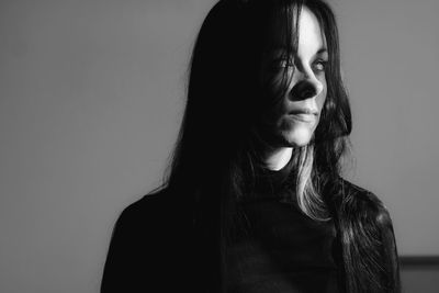 Portrait of young woman standing against black background