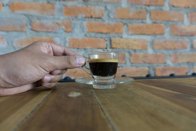 Cropped hand holding black coffee at table