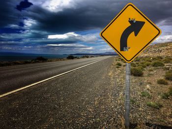 Close-up of road sign by sea against sky