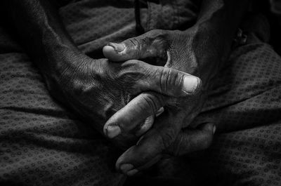 Close-up of clasped hands on bed