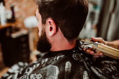 Cropped hands of barber grooming customer in salon