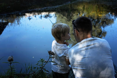 Rear view of father and son in water