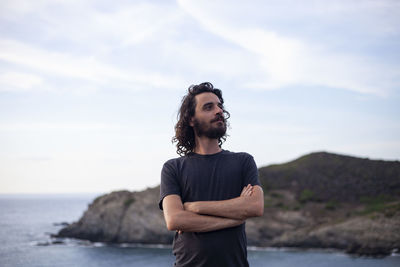Young man standing in sea against sky
