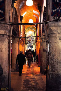 Rear view of people walking in alley amidst buildings