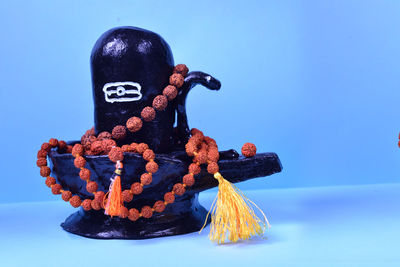 Close-up of figurine against blue sky over white background