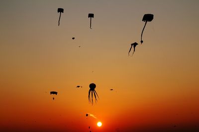 Silhouette birds flying against sky during sunset