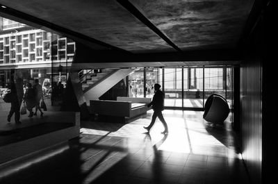 Silhouette man and woman walking on tiled floor in city