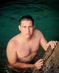 Portrait of young shirtless man in lake