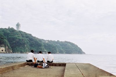 People relaxing on calm beach against sky