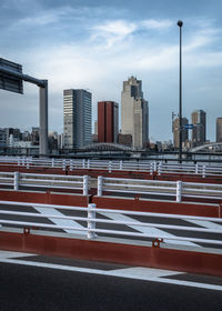 Road by buildings against sky in city