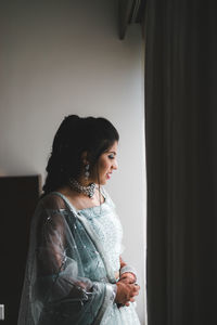 Side view of young woman looking at home thru the window