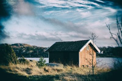 Houses on field against cloudy sky